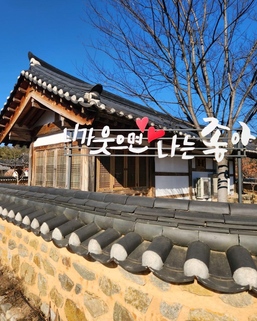 겨울 맑은 날의 한옥과 기와 돌담, 잎 진 나무, 한옥 앞 조형 글자